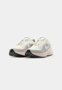 Lichtbeige hardloopschoenen met een mesh-bovenwerk, witte accenten en een zwarte rubberen zool. Voorzien van platte veters en een iets gewatteerde zool.