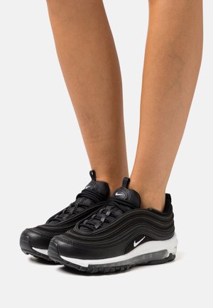 Des baskets Nike Air Max 97 noires présentent un design en couches avec une tige en mesh et en cuir, une semelle intermédiaire blanche et une semelle extérieure en caoutchouc noir.
