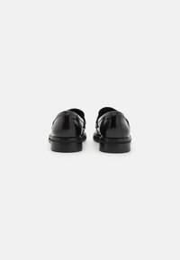 Czarne lakierowane buty na gładkim wykończeniu, z okrągłym noskiem i niskim gumowym obcasem, posiadające staranne szwy i minimalistyczny design.