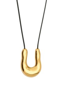 Lesklý zlacený zakřivený U-tvarovaný přívěsek zavěšený na tenkém černém šňůrovém náhrdelníku na bílém pozadí.