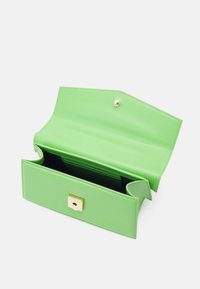 Borsa in pelle verde con una chiusura dorata, caratterizzata da una texture liscia e un ampio interno, parzialmente aperta per mostrare la foderatura nera e i compartimenti.