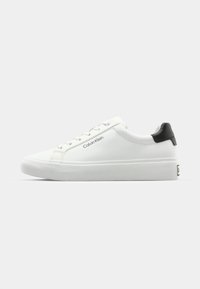 Bijele tenisice s glatkom površinom, crnim naglaskom na peti i dizajnom vezanja. Sadrže "Calvin Klein" oznaku sa strane. Minimalistički stil.