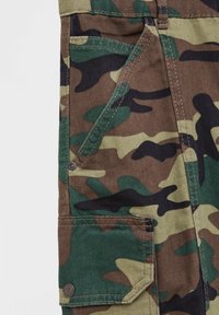 Camouflage cargo pants met een mix van groene, bruine en zwarte patronen. Bevat meerdere zakken en knoopaccenten.