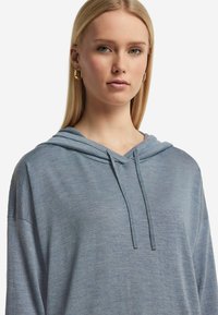 Ljusblå huva sweatshirt med en avslappnad passform, mjuk textur och justerbara snoddar vid halsen. Har en enkel design utan mönster.