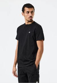 Sort bomulds-T-shirt med rund hals og korte ærmer, med et lille logo på brystet og en glat tekstur.