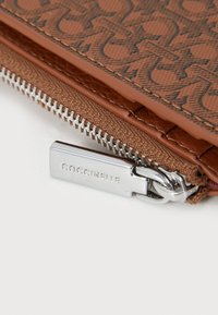 Brown patterned zippered pouch with a smooth surface, silver hardware, and a logo visible on the zipper pull.