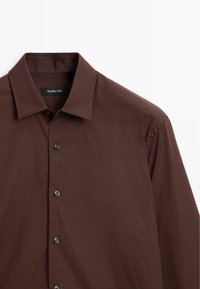 Mørkebrunt skjorte med knapper, featuring en klassisk krave, glat tekstur og mørke knapper, med en diskret glans i stoffet.