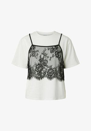 Tricou alb cu mânecă scurtă suprapus cu o camisole scurtă din dantelă neagră florală, cu bretele subțiri și tiv cu margine ondulată.