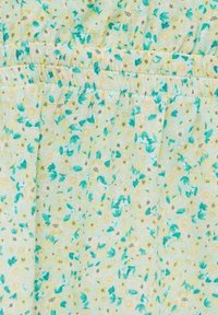 Tissu bleu clair avec de petites fleurs jaunes et des feuilles vertes, présentant des coutures élastiques froncées près du bord supérieur.
