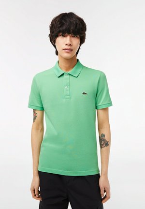 Polo verde hecho de tela texturizada, con cuello, placket de tres botones y un pequeño logo bordado en el pecho.
