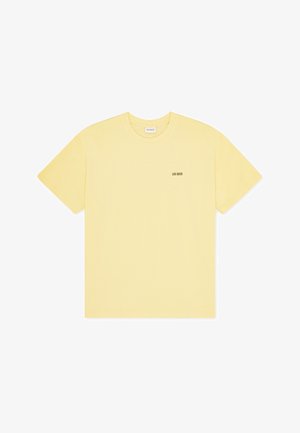 T-shirt en coton jaune à manches courtes, col rond, avec un petit logo noir "LES DEUX" imprimé sur le côté gauche de la poitrine.