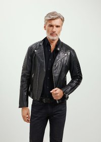 Czarna skórzana kurtka motocyklowa z pikowanymi akcentami na ramionach, frontowymi zamkami błyskawicznymi i szerokim kołnierzem. Noszona na zapinanej czarnej koszuli i ciemnych dżinsach.