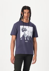 Navy cotton t-shirt featuring a large black-and-white graphic of two people on the front, with the text "oasis" below the image.