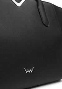Černá textura kabelka s prvkem stříbrného loga a elegantním designem s horní rukojetí. Detaily zahrnují emblém ve tvaru V.