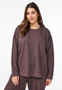 Haut à manches longues, ample, en tissu mauve profond avec un col rond et une texture douce, associé à un bas assorti.
