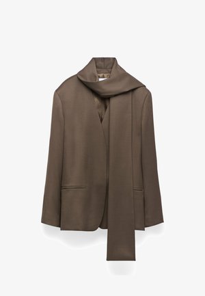 Veste tailleur marron avec un large col en écharpe drapé, fermeture à un bouton et deux poches avant. Tissu lisse avec une finition mate.