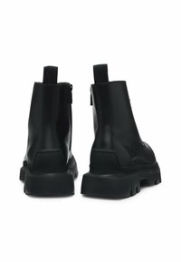 Black leather ankle boots with a sturdy rubber sole, zip closure, and a pull tab at the back. Smooth texture with minimal stitching details.