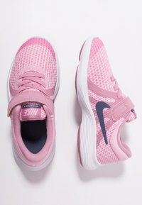 Růžové běžecké boty Nike pro děti s síťovinou, suchými zipy a bílými podrážkami, zobrazené z horního a bočního pohledu na bílém pozadí.