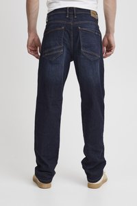 Jeans de mezclilla azul oscuro con un diseño de pierna recta, que cuentan con dos bolsillos traseros y costuras amarillas contrastantes. La tela tiene una textura suave.