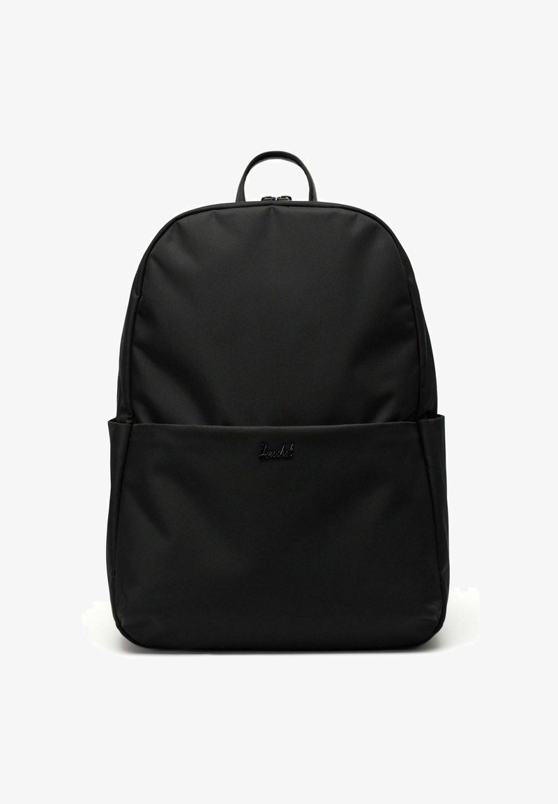 Sac à dos en nylon noir au design minimaliste, avec une poignée supérieure, une poche avant et un logo discret. Texture lisse et forme épurée.
