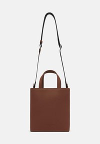 Brązowa skórzana torebka w kwadratowym kształcie, z krótkimi uchwytami u góry i odpinanym czarnym paskiem. Gładka tekstura, minimalistyczny design, brak widocznych elementów metalowych.
