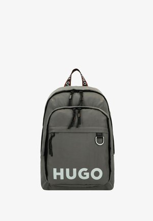Sac à dos en nylon gris avec des tirettes de fermeture éclair noires et une poche avant. Grand logo blanc "HUGO" et sangle contrastante avec branding.