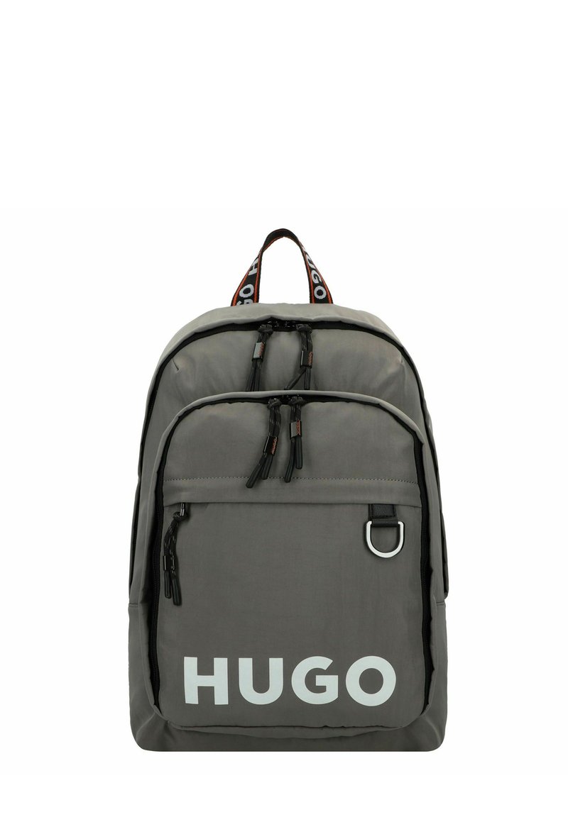 Zaino in nylon grigio con zip nere e una tasca frontale. Grande logo bianco "HUGO" e tracolla a contrasto con branding.