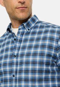 Blaue und weiße kariert Flanellbluse mit einem Button-Down-Kragen, ausgestattet mit schwarzen Knöpfen und einer weichen Textur.
