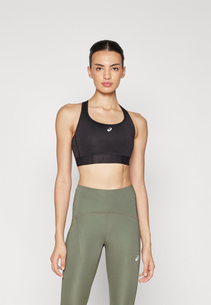 Black sports bra with wide straps and logo, paired with olive green high-waisted leggings featuring a side pocket and contrast stitching.