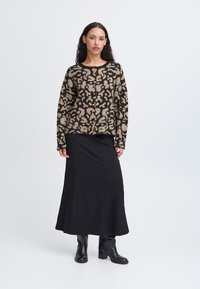 Maglione a fantasia leopardata marrone e nera con dettagli a bottoni, abbinato a una gonna nera a metà coscia e stivaletti neri.