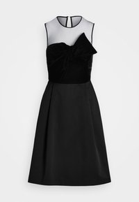 Svart klänning med en genomskinlig mesh-bodice och en tubtopp i sammet med ett stort rosett-detall. En utsvängd kjol skapar en A-linjeformad siluett.