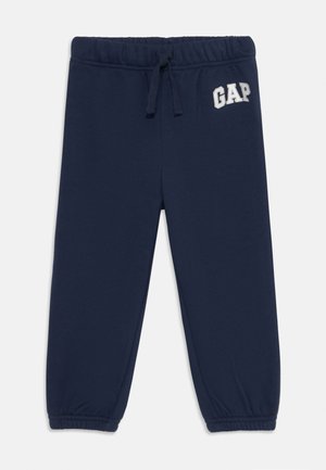 Navy blue sweatpants with an elastic waistband, drawstring, and elastic cuffs. Features embroidered "GAP" logo on the front. Soft fabric.