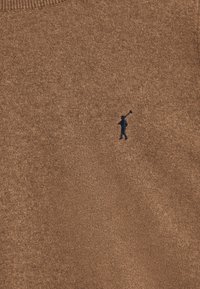 Brązowy dziany sweter o teksturowanym wykończeniu. Na dolnej lewej stronie znajduje się małe granatowe logo przedstawiające postać trzymającą kij golfowy.