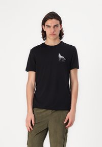 Zwarte katoenen T-shirt met een witte grafiek van een wolf op de linkerborst. Korte mouwen en een ronde halslijn. Eenvoudig, aansluitend ontwerp.