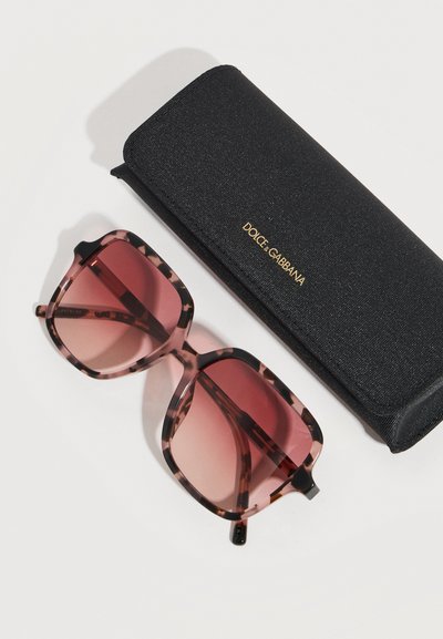 Γυαλιά ηλίου oversized τετράγωνα με σχέδιο χελώνας και ροζ φακούς με διαβάθμιση, δίπλα σε μαύρη θήκη Dolce & Gabbana με υφή.