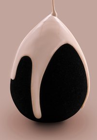 Spugna per trucco nera a forma di goccia, con un fluido crema chiaro che cola dalla cima. Texture morbida e superficie liscia.
