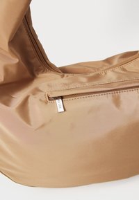 Brun dragkedjefodral i slätt, glänsande tyg; har en silverfärgad dragkedja med logotyp och en enkel, rundad design.