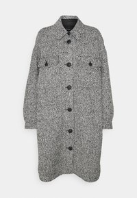 Manteau texturé noir et blanc avec un col, fermeture à bouton sur le devant, deux poches à rabat et manches longues. Le tissu présente un motif pied-de-poule.