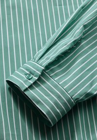 Zielona, w poziome paski, koszula z długim rękawem z białymi paskami, z bawełnianego materiału, z mankietami na guziki i gładką fakturą.