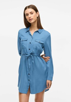 Svetlo modra, dolgosleeve denim obleka z gumbnim zapenjanjem spredaj, dvema prsnih žepoma in detajlom na vezanje v pasu. Gladka tekstura in sproščen dizajn.