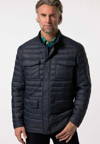 Marineblaue Steppjacke mit einem gesteppten Design, zwei aufgesetzten Taschen und einem Reißverschluss vorne. Sie verfügt über einen Stehkragen und eine glatte, glänzende Textur.