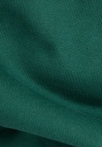 Tessuto a costine verde scuro con una texture morbida; motivo a maglia visibile e caduta fluida, che indica un materiale flessibile ed elastico.