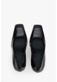 Czarne skórzane buty typu slingback z kwadratowym noskiem, gładką powierzchnią i wycięciami po bokach dla wentylacji. Smukły i minimalistyczny design.