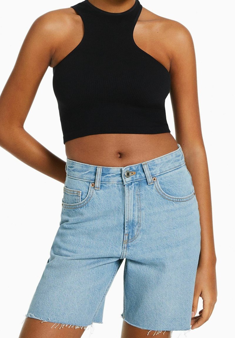 Schwarzes, geripptes Halfter-Crop-Top, kombiniert mit hochgeschnittenen, hellblauen Denim-Shorts mit fransenbesäumtem Saum und frontalen Taschen.