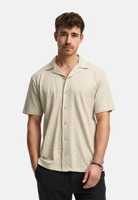 Korte mouw, knoopsluiting overhemd in lichtbeige met een gestructureerd patroon en een casual kraag. Gemaakt van ademende stof, heeft een ontspannen pasvorm.