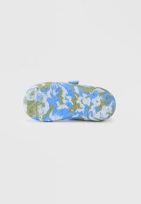 Μπλε και πράσινη σόλα παπουτσιού με σχέδιο, με υφή και στρογγυλεμένη μύτη. Λεπτομέρεια με ιμάντα βέλκρο ορατή στο πίσω μέρος.