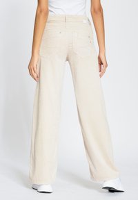 Light beige corduroy wide-leg pants with a textured finish, featuring back pockets and a smooth waistband. Available in a casual style.