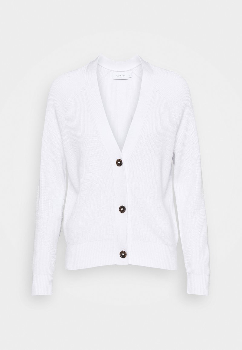 Cardigan blanc en tricot avec manches longues, col en V, et trois boutons foncés sur le devant, présenté sur un fond neutre.