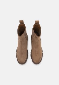 Bottes cheville en cuir marron avec une finition texturée, des panneaux latéraux élastiques et des languettes sur le devant, dotées d'une semelle en caoutchouc épaisse.