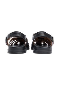 Μαύρα δερμάτινα σανδάλια με ρυθμιζόμενες λουρίδες, ανοιχτή πίσω όψη και υφασμένο πέλμα. Διαθέτουν μαύρη, στιβαρή σόλα με λεία επιφάνεια.
